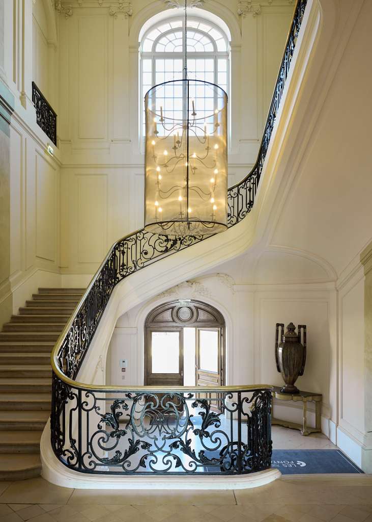 Wrought-iron staircase at the 19th-century Château Rothschild, bathed in natural light.