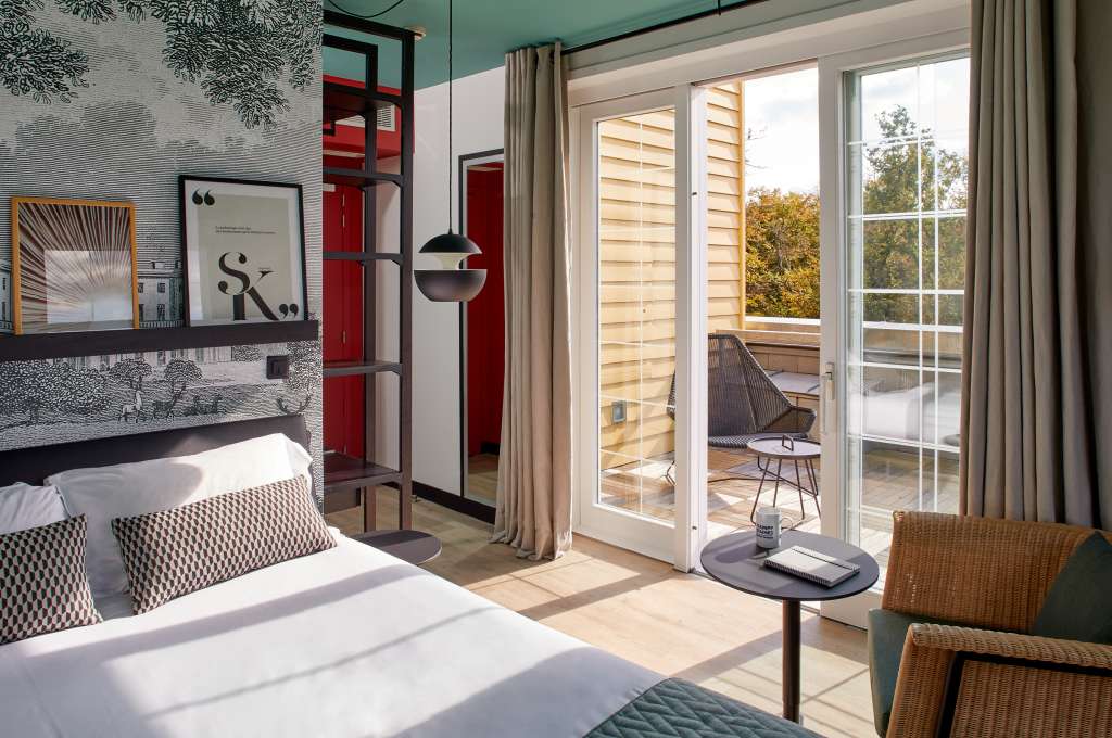 Chambre spacieuse avec fauteuil et grandes fenêtres, idéale pour héberger les participants à un séminaire au vert.