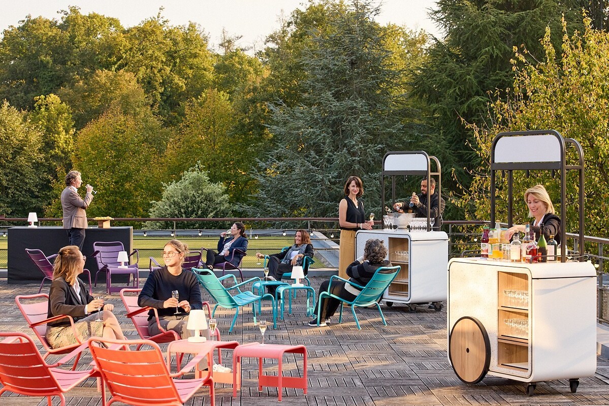 Participants réunis sur la grande terrasse du domaine Les Fontaines, profitant d’un apéritif avec vue sur le parc arboré