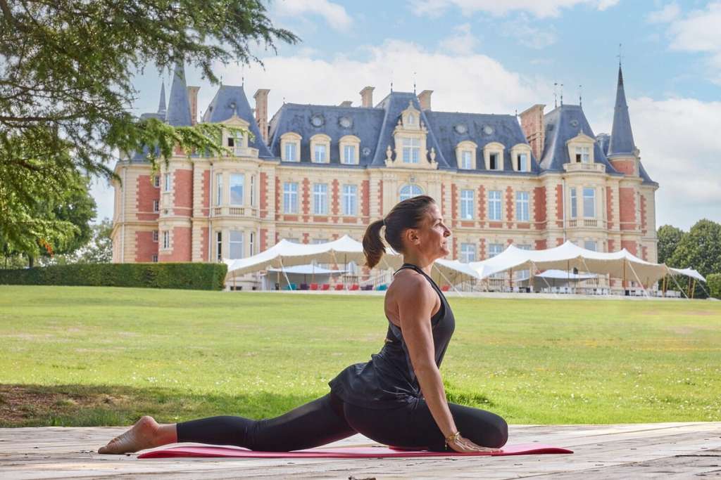 Participant en pleine séance de yoga dans le parc arboré du domaine Les Fontaines, dans un cadre apaisant propice au ressourcement