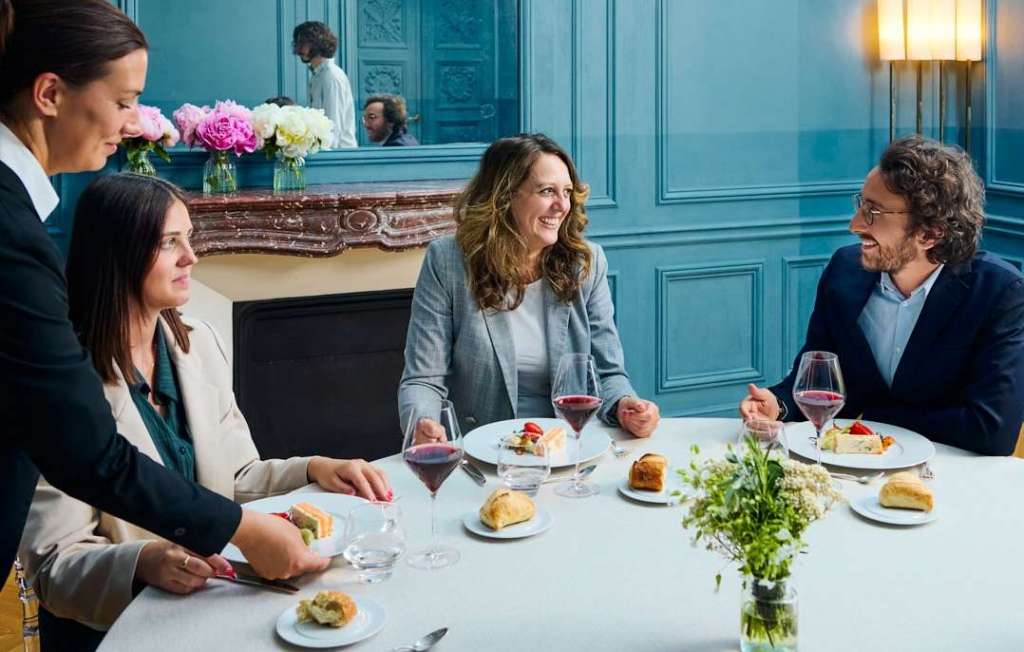 Moment de convivialité avec trois personnes discutant autour d’une table dans une salle élégante du Château.
